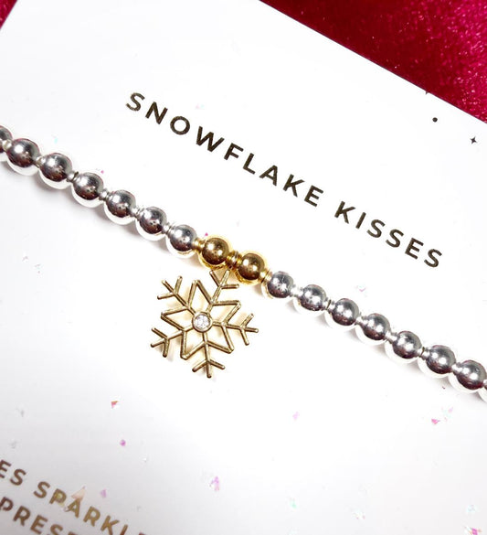 Bracelet with gold snowflake charm on a white card with text